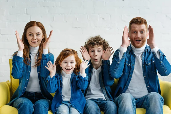 Funny family sitting on sofa and playing peek-a-boo — Stock Photo