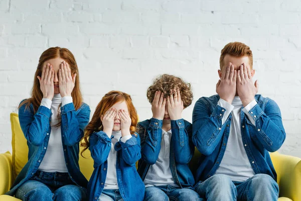 Famiglia seduta sul divano e che copre i loro volti — Foto stock