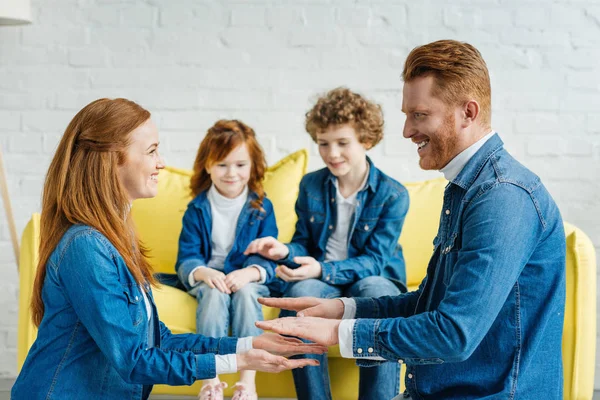 Los padres se divierten mientras los niños se sientan en el sofá - foto de stock