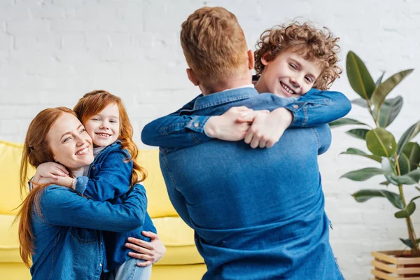 Lindos padres de familia e hijos abrazando en casa - foto de stock