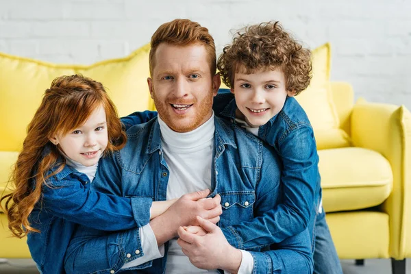 Lindos niños abrazando a su joven padre - foto de stock