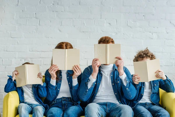 Famiglia che tiene libri e si siede sul divano — Foto stock