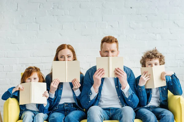 Família sentada no sofá e segurando livros — Fotografia de Stock