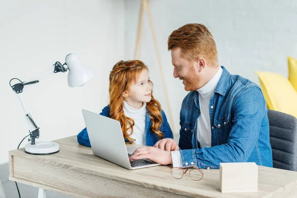 Father and child talking by table with laptop — Stock Photo