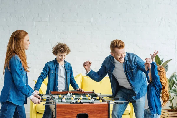 Niños y padres jugando futbolín juntos - foto de stock