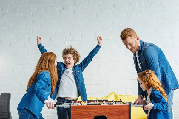 Happy family enjoying time together while playing foosball — Stock Photo