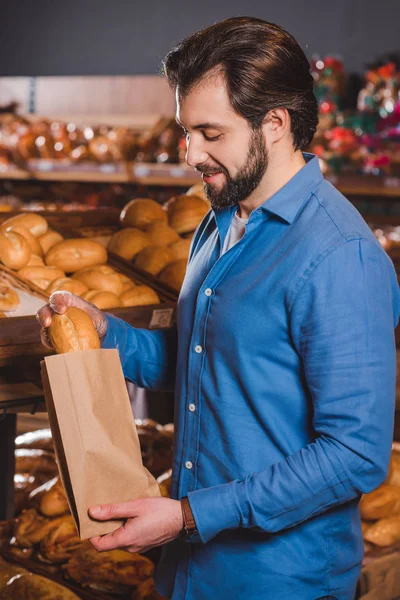 Вид збоку усміхненого чоловіка, який вибирає хліб у гіпермаркеті — стокове фото