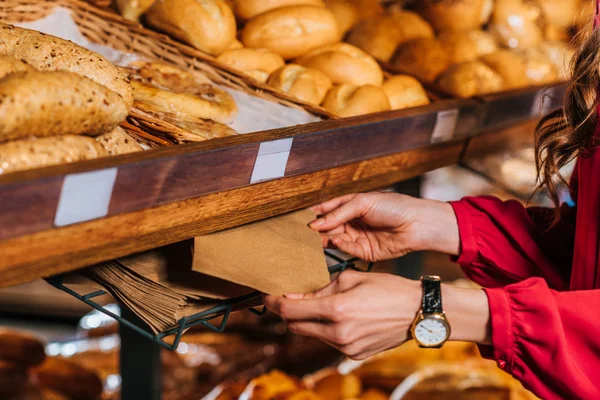Partial view of woman taking paper bag for bread while shopping in supermarket — Stock Photo