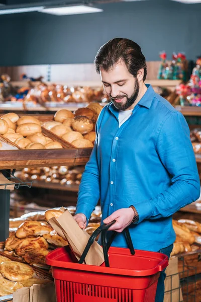 Uomo mettere pagnotta di pane nel carrello della spesa nel supermercato — Foto stock