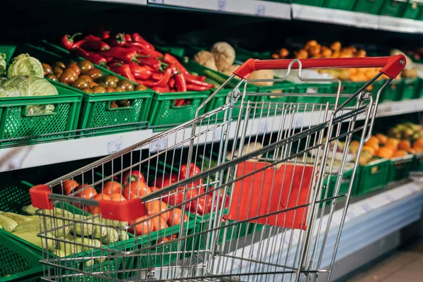 Вибірковий фокус порожнього кошика і свіжих овочів в супермаркеті — Stock Photo