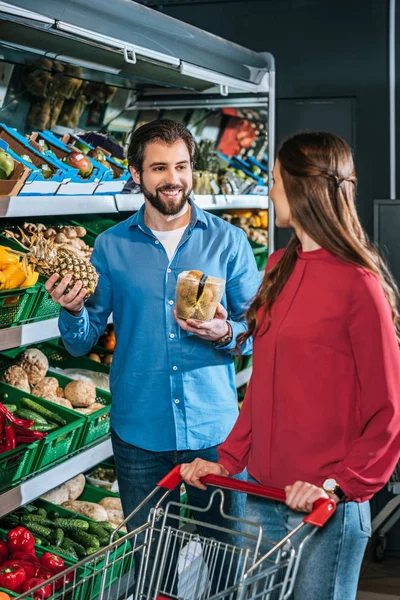 Casal com carrinho de compras com compras juntos no supermercado — Fotografia de Stock