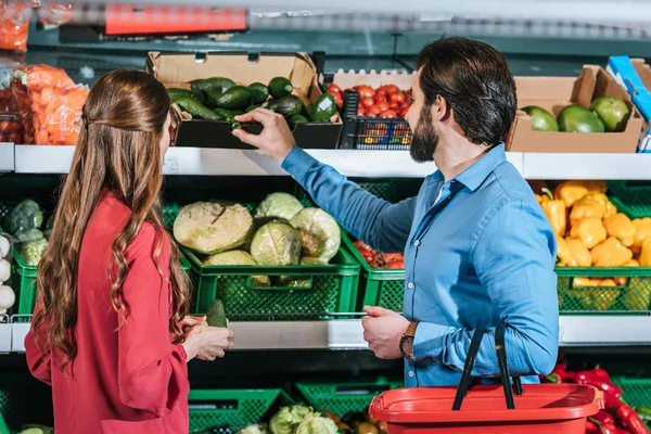 Visão traseira do casal com compras cesta compras juntos no supermercado — Fotografia de Stock