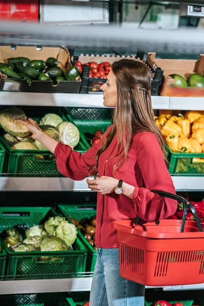 Mulher escolhendo vegetais frescos crus no supermercado — Fotografia de Stock