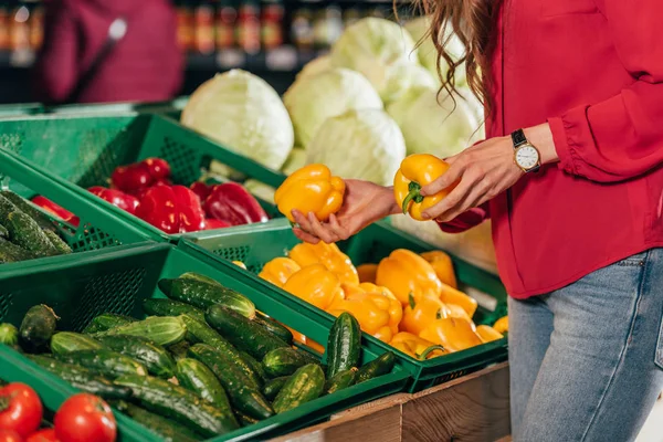 Vue partielle du client choisissant des poivrons crus frais dans l'hypermarché — Photo de stock