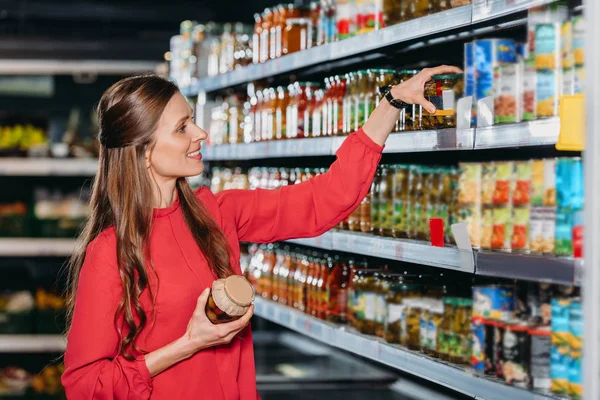 Donna sorridente che sceglie i prodotti nell'ipermercato — Foto stock