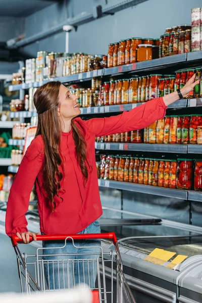 Woman with shopping trolley shopping in supermarket — Stock Photo