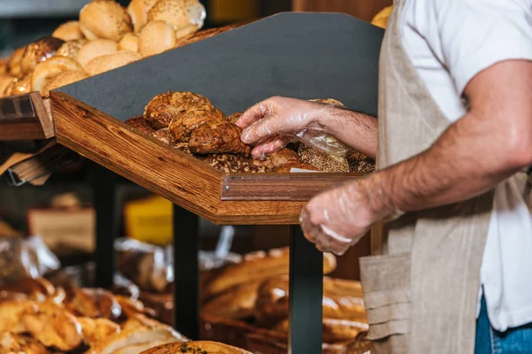 Cropped shot of male shop assistant arranging pastry in supermarket — Stock Photo