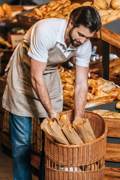 Assistant de magasin masculin arrangeant la pâtisserie fraîche dans le supermarché — Photo de stock