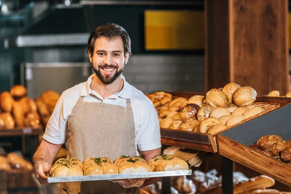 Retrato del asistente de tienda sonriente organizando pastelería fresca en el supermercado - foto de stock