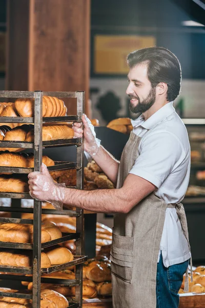 Sorrindo assistente loja masculino organizar pastelaria fresca no supermercado — Fotografia de Stock