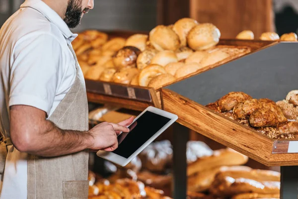 Cropped shot of shop assistant in apron using tablet with blank screen in supermarket — Stock Photo