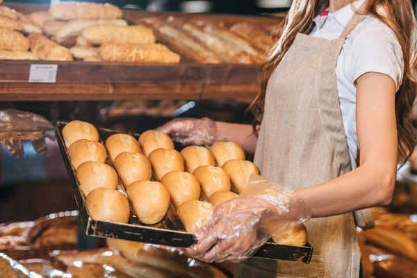 Partial view of shop assistant arranging loafs of bread in shopping market — Stock Photo