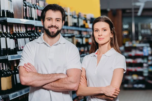 Portrait of smiling shop assistants with arms crossed in hypermarket — Stock Photo