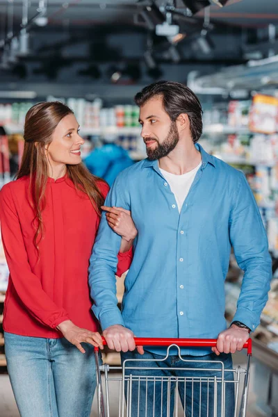 Retrato de pareja con carrito de compras juntos en el supermercado - foto de stock