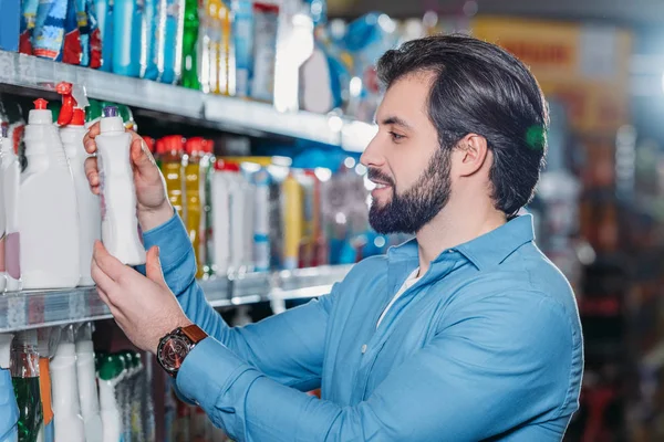 Vista lateral del hombre la elección de detergente en el hipermercado - foto de stock