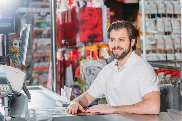 Retrato del asistente de tienda masculino sonriente en el cajero automático en el supermercado - foto de stock