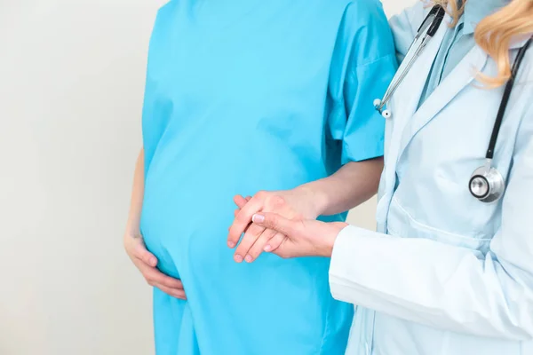 Plan recadré de gynécologue obstétricien aidant la femme enceinte à marcher et tenant sa main — Photo de stock