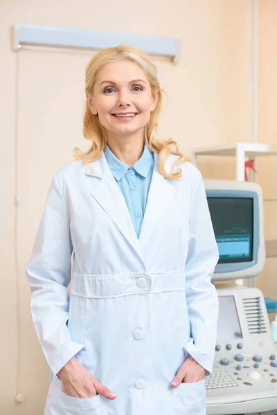 Zufriedene Ärztin blickt in Ultraschalluntersuchungsbüro in die Kamera — Stockfoto