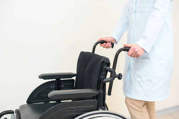 Обрізаний знімок жінки-лікаря з інвалідним візком на білому — стокове фото