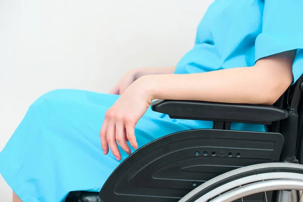 Tiro recortado de la mujer embarazada en el abrigo médico sentado en silla de ruedas - foto de stock
