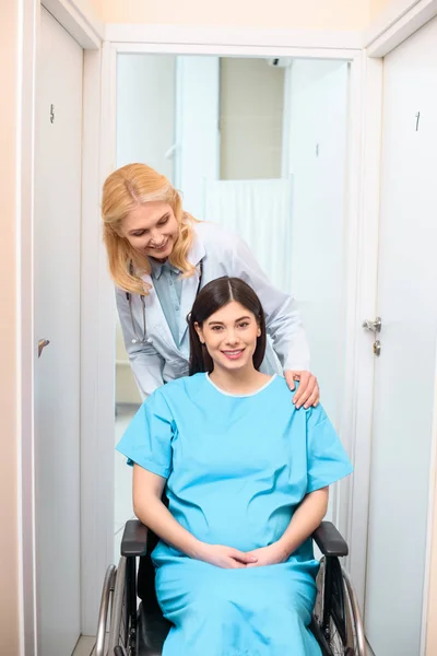 Ostetrico ginecologo guida donna incinta sulla sedia a rotelle presso l'ospedale di maternità e sostenerla — Foto stock