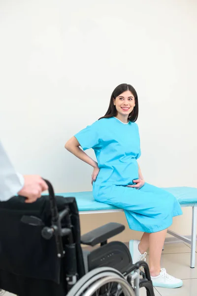 Mulher grávida olhando para ginecologista obstetra com cadeira de rodas — Fotografia de Stock