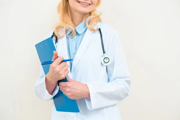 Schnappschuss einer lächelnden Ärztin mit Klemmbrett auf Weiß — Stockfoto