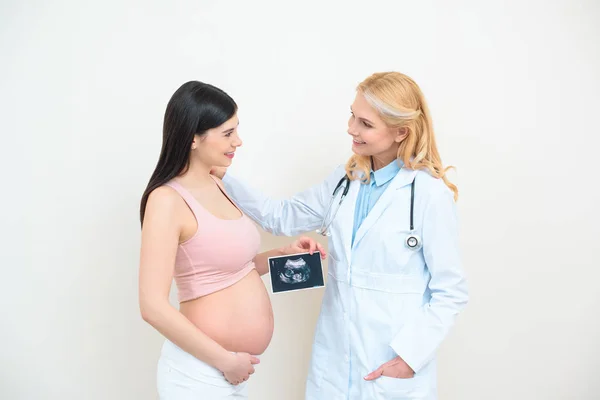 Ginecólogo obstetra y mujer embarazada joven con imagen de ecografía - foto de stock