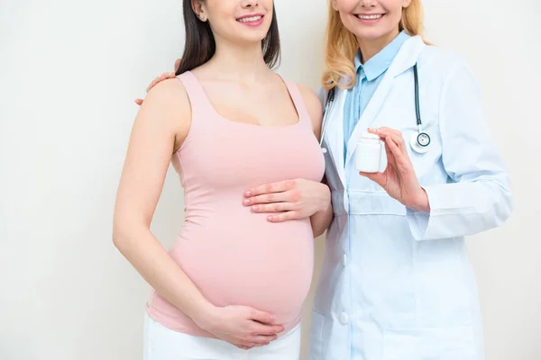 Tiro cortado de ginecologista obstetra e mulher grávida segurando frasco de pílulas — Fotografia de Stock