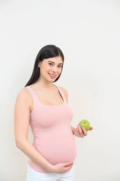 Glückliche junge schwangere Frau mit grünem Apfel auf weißem Grund — Stock Photo