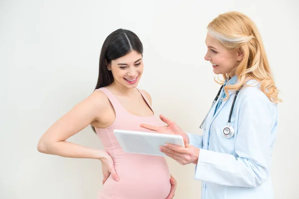 Ginecologista obstetra feliz e mulher grávida usando tablet juntos — Fotografia de Stock