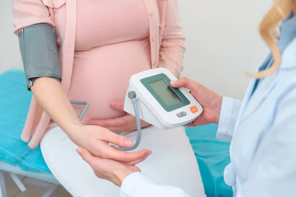 Inyección recortada de ginecólogo obstetra medición de la presión arterial de la mujer embarazada en la clínica - foto de stock