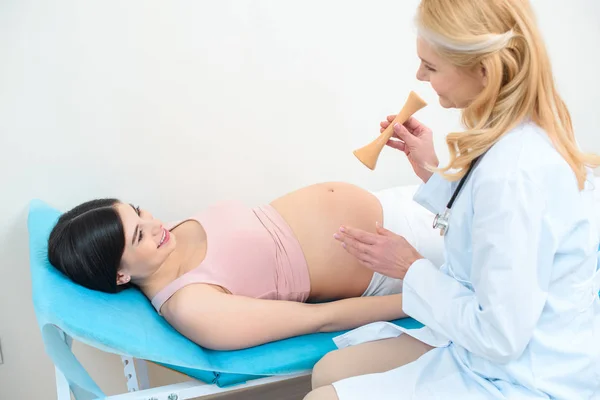 Ginecologista obstetra com estetoscópio tipo traube e mulher grávida — Fotografia de Stock