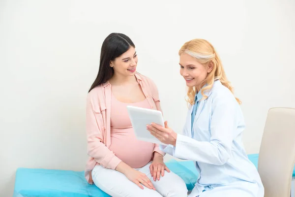 Ginecólogo obstetra y mujer embarazada usando tableta juntos - foto de stock