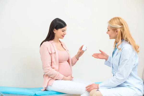 Gynécologue obstétricien montrant pot de pilules à la femme enceinte — Photo de stock