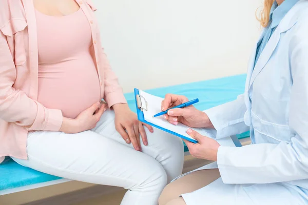 Обрезанный снимок акушера-гинеколога, консультирующего беременную женщину в клинике — стоковое фото