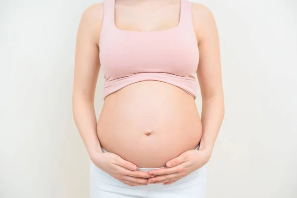 Tiro cortado de mulher grávida segurando sua barriga no branco — Fotografia de Stock