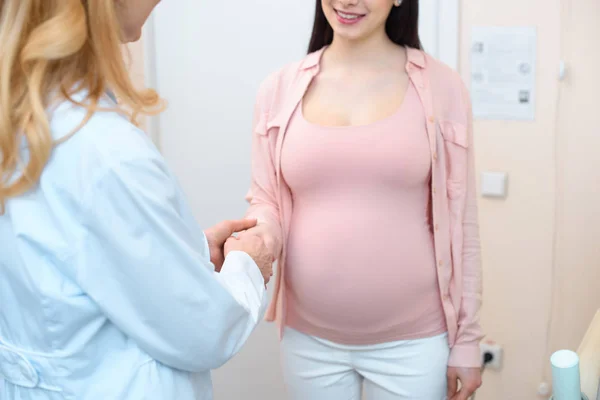 Cropped shot of obstetrician gynecologist and pregnant woman shaking hands — Stock Photo