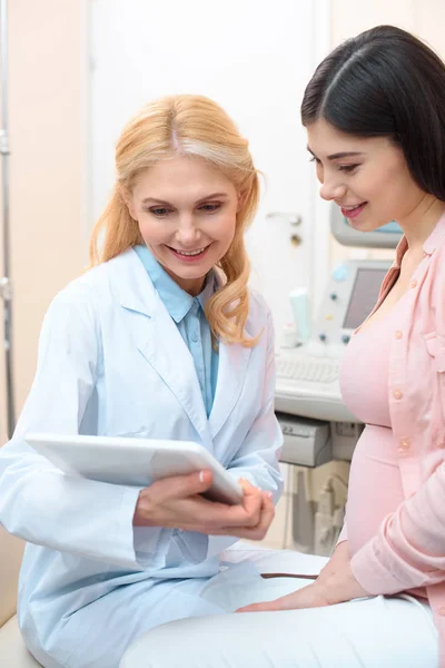 Ginecólogo obstetra y mujer embarazada usando tableta juntos - foto de stock