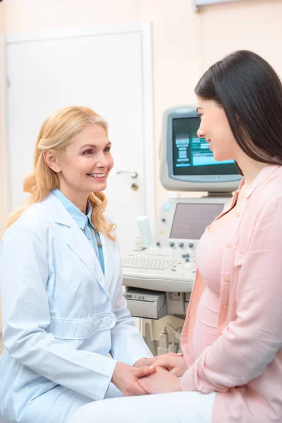 Sorridente ostetrica matura ginecologo sostenere donna incinta — Foto stock